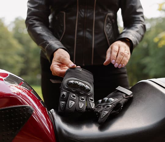 Fotografía de una mujer quitándose los guantes de un asiento de motocicleta.