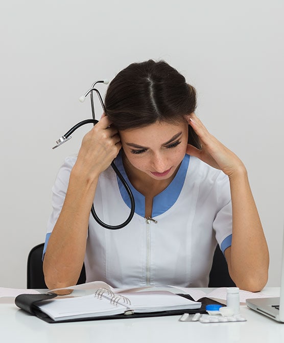 Fotografía de una doctora con la cabeza entre las manos, relacionada con una demanda por error de diagnóstico.