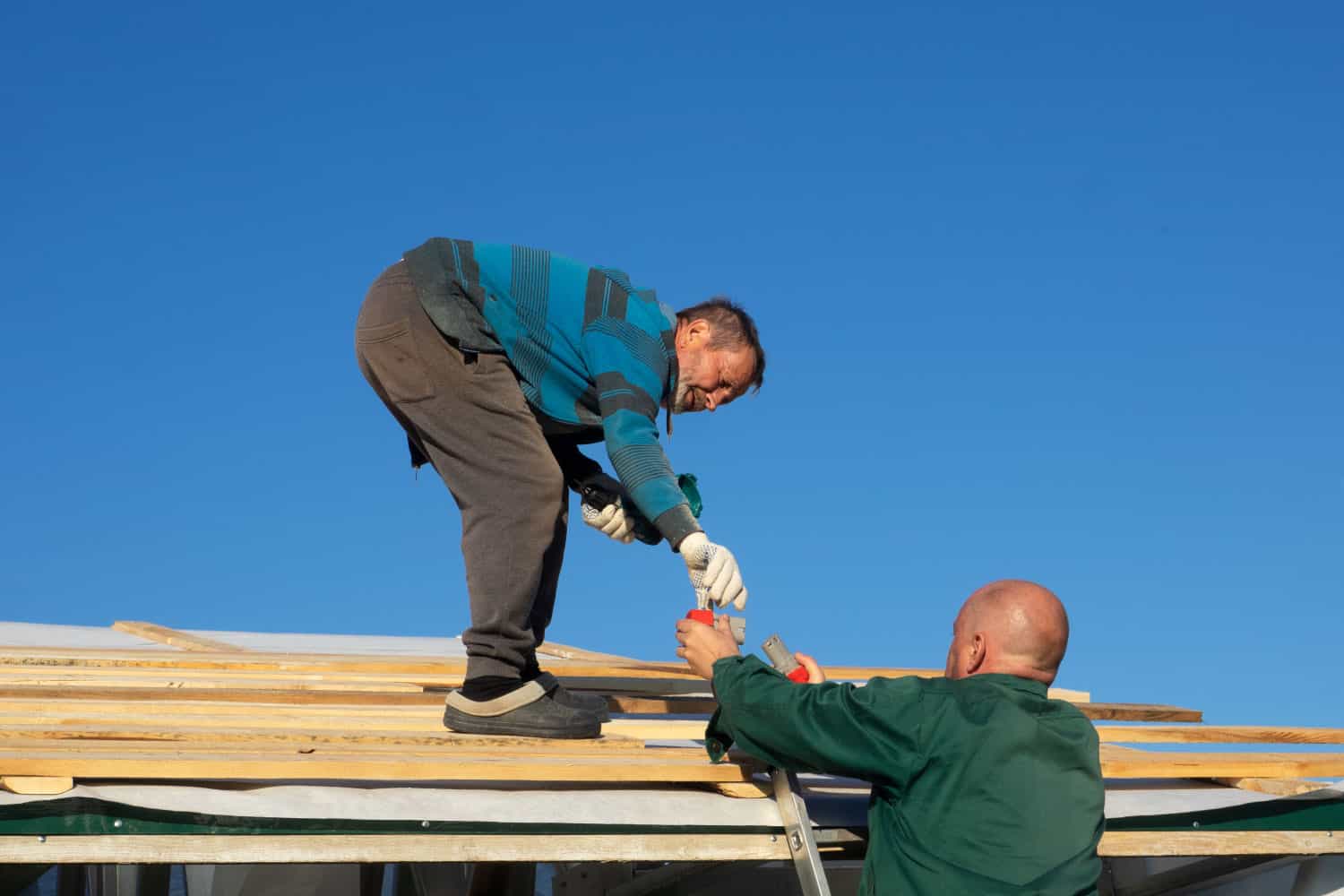 Photo of two workers fixing a damaged roof after a storm in Oklahoma.